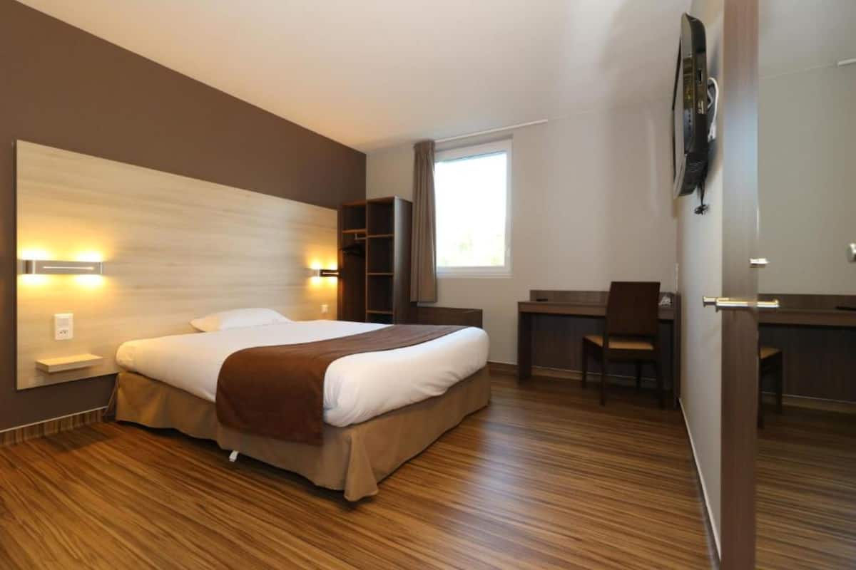 Une chambre d’hôtel avec un grand lit, un bureau et une chaise.