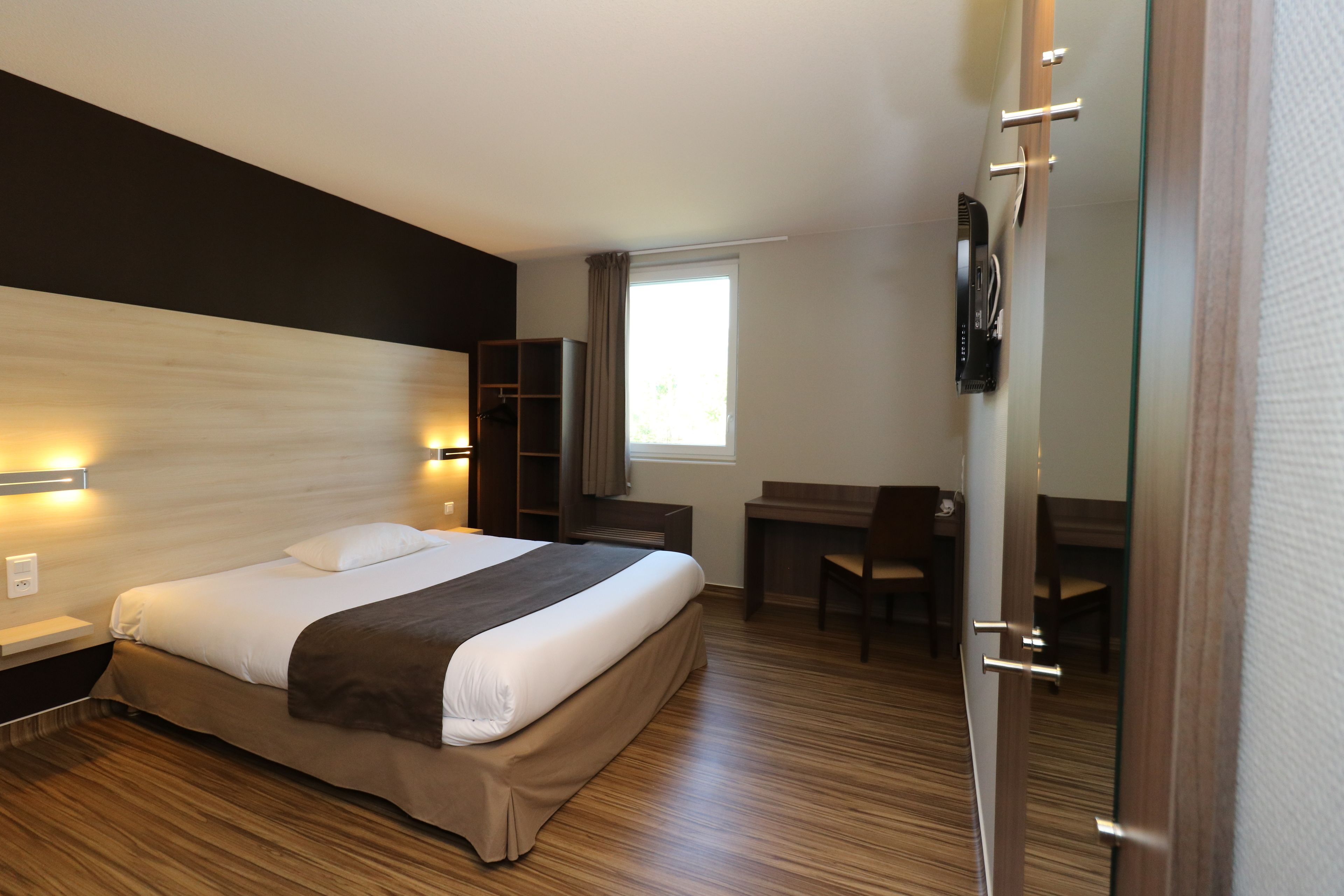 A modern hotel room with a large bed, bedside tables, a desk, and a chair.