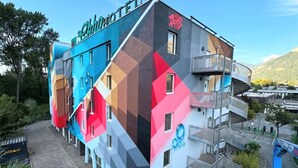 A modern hotel with a colorful geometric facade, a visible outdoor area, and a sign indicating it is a hotel. - Ekho Hotel Grenoble Nord Saint Egrève (Saint-Egreve)