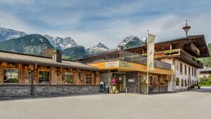 Un edificio tradicional de madera con balcón, fachada de piedra y vistas a la montaña.