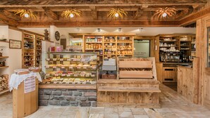 Una panadería con estantes de madera llenos de productos horneados y un expositor repleto de pasteles.
