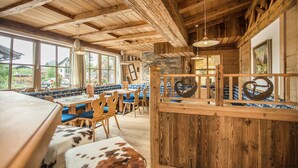 Un interior rústico de madera con un comedor que incluye sillas azules y un banco tapizado en cuero de vaca.
