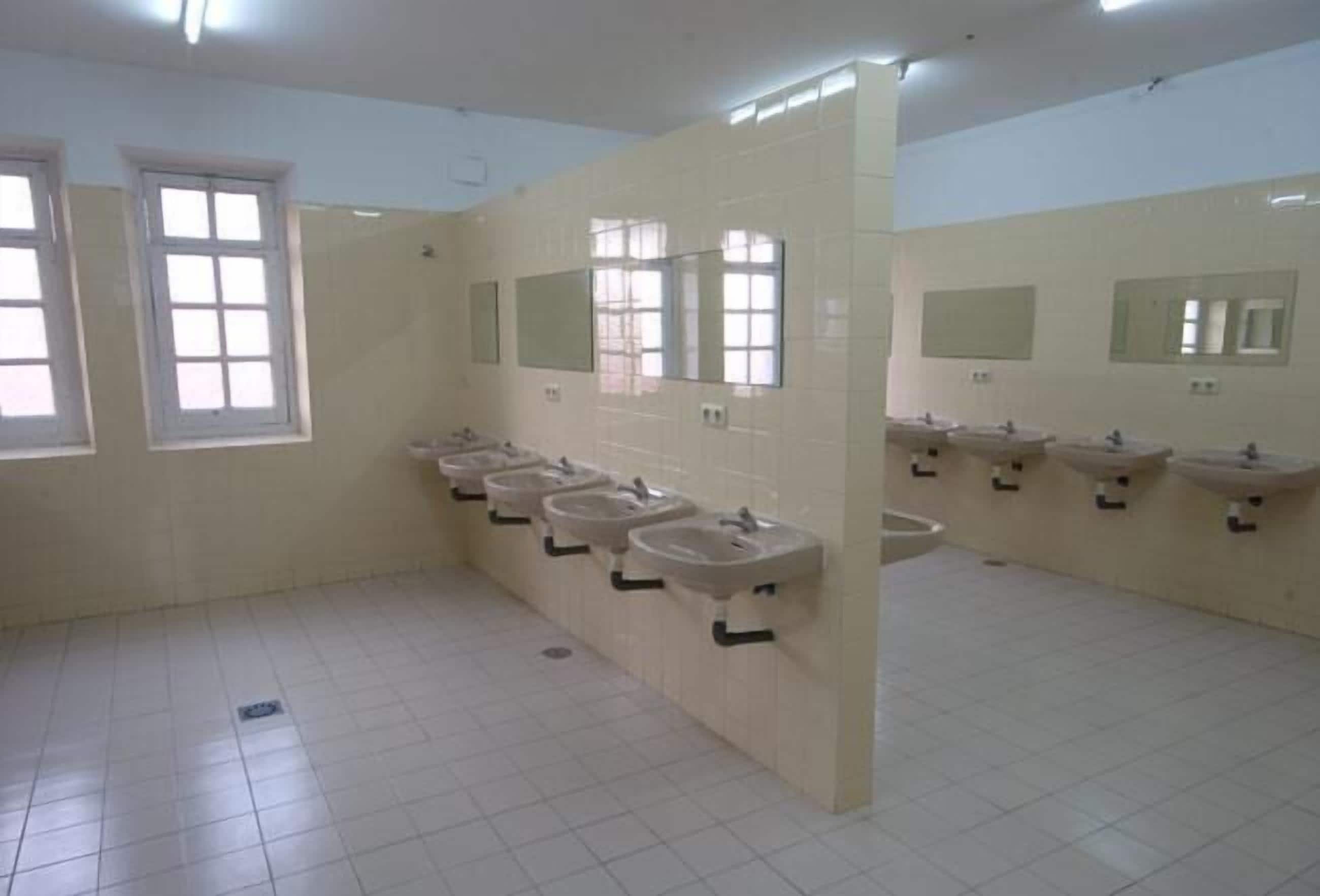 A public restroom with multiple sinks and mirrors, tiled walls, and windows.