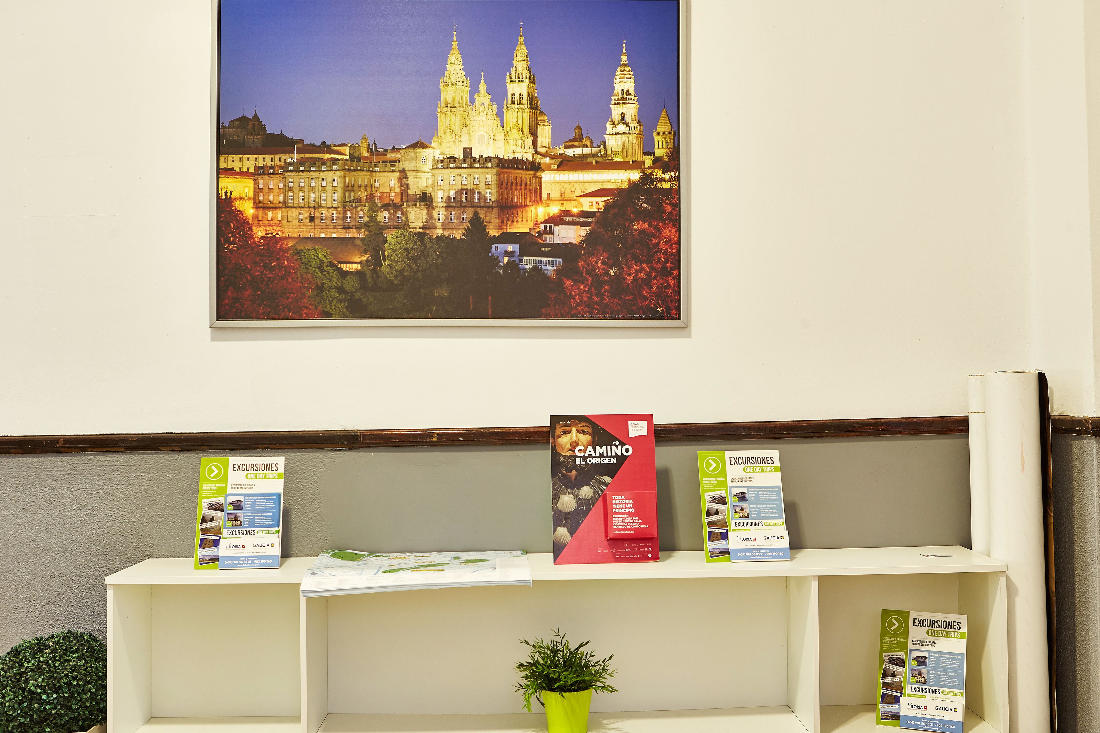A reception desk with brochures and a framed picture of a historic building.