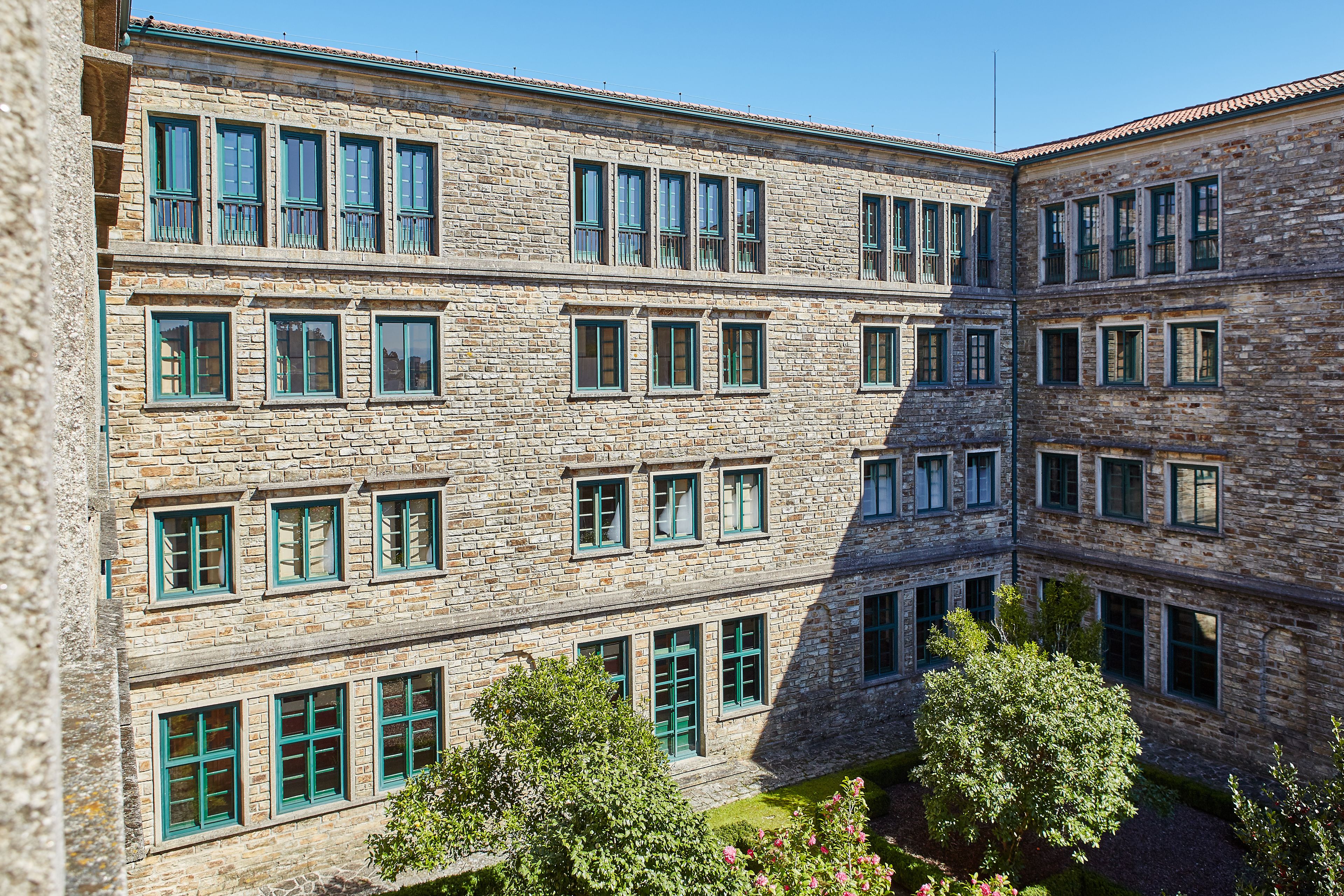 Un edificio de varios pisos de piedra con numerosas ventanas y un patio.
