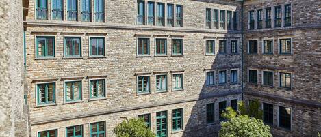Un edificio de varios pisos de piedra con numerosas ventanas y un patio.