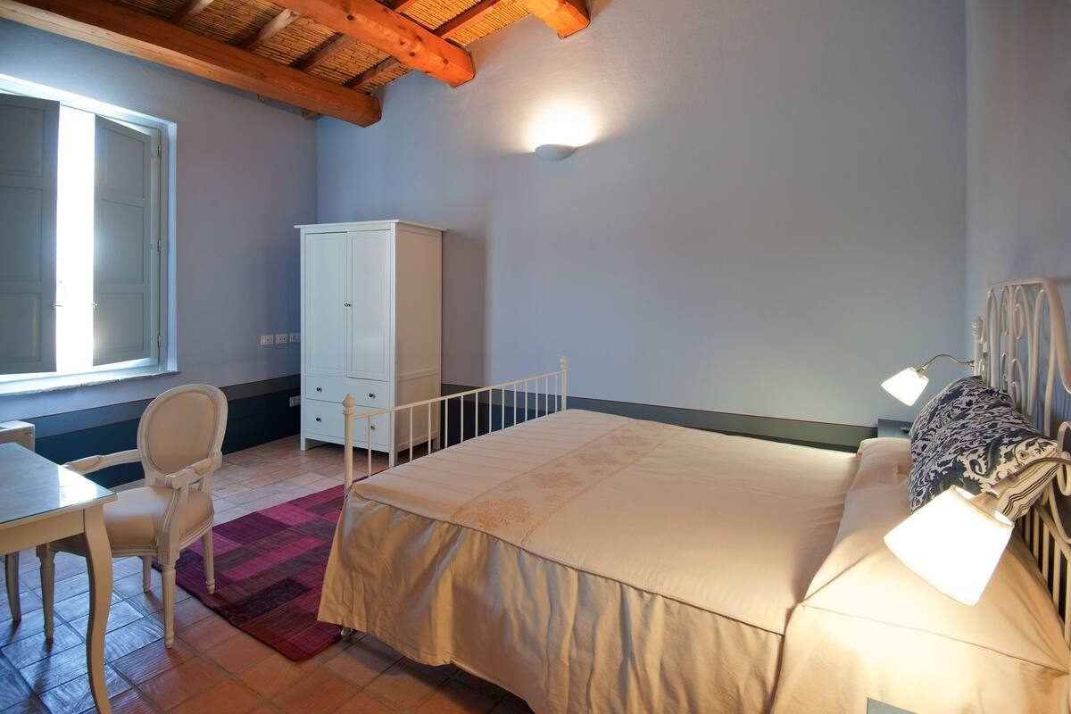 Ein Schlafzimmer mit Bett, Schreibtisch, Stuhl, Kleiderschrank und Fenster.