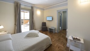 Habitación de hotel con cama, escritorio, silla, televisión y vista al exterior.