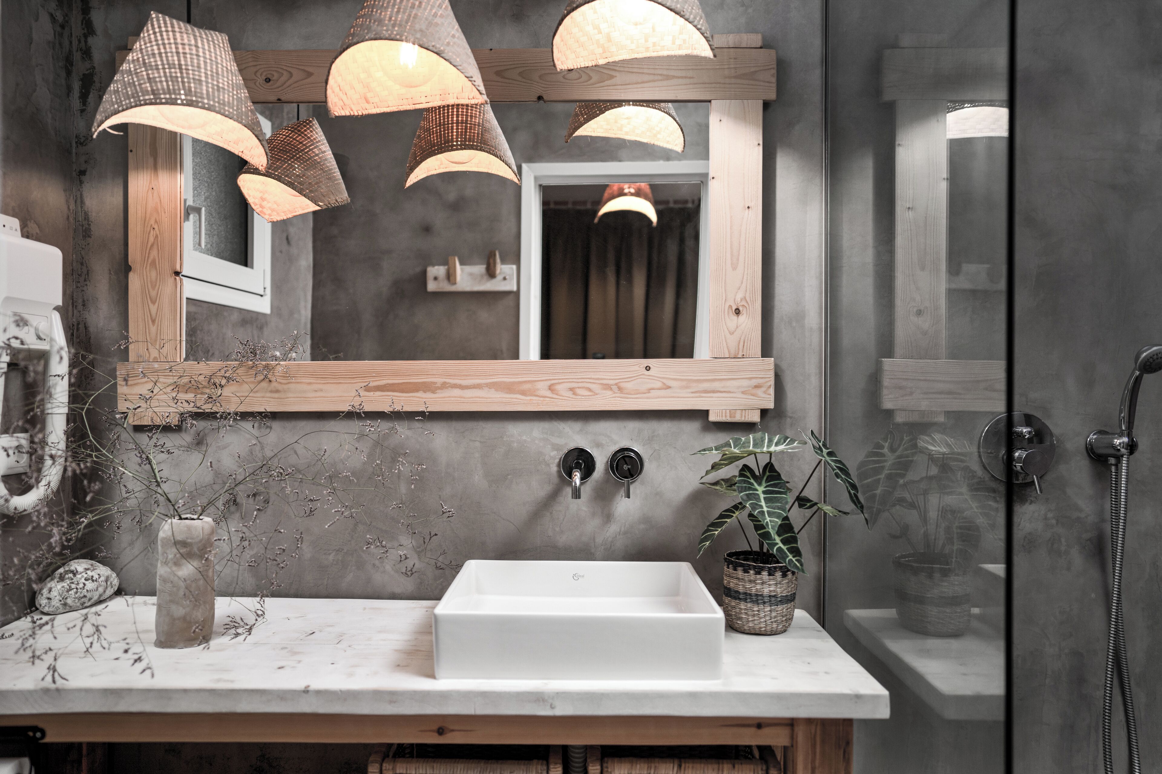 A bathroom with a white sink, wooden vanity, and pendant lights.
