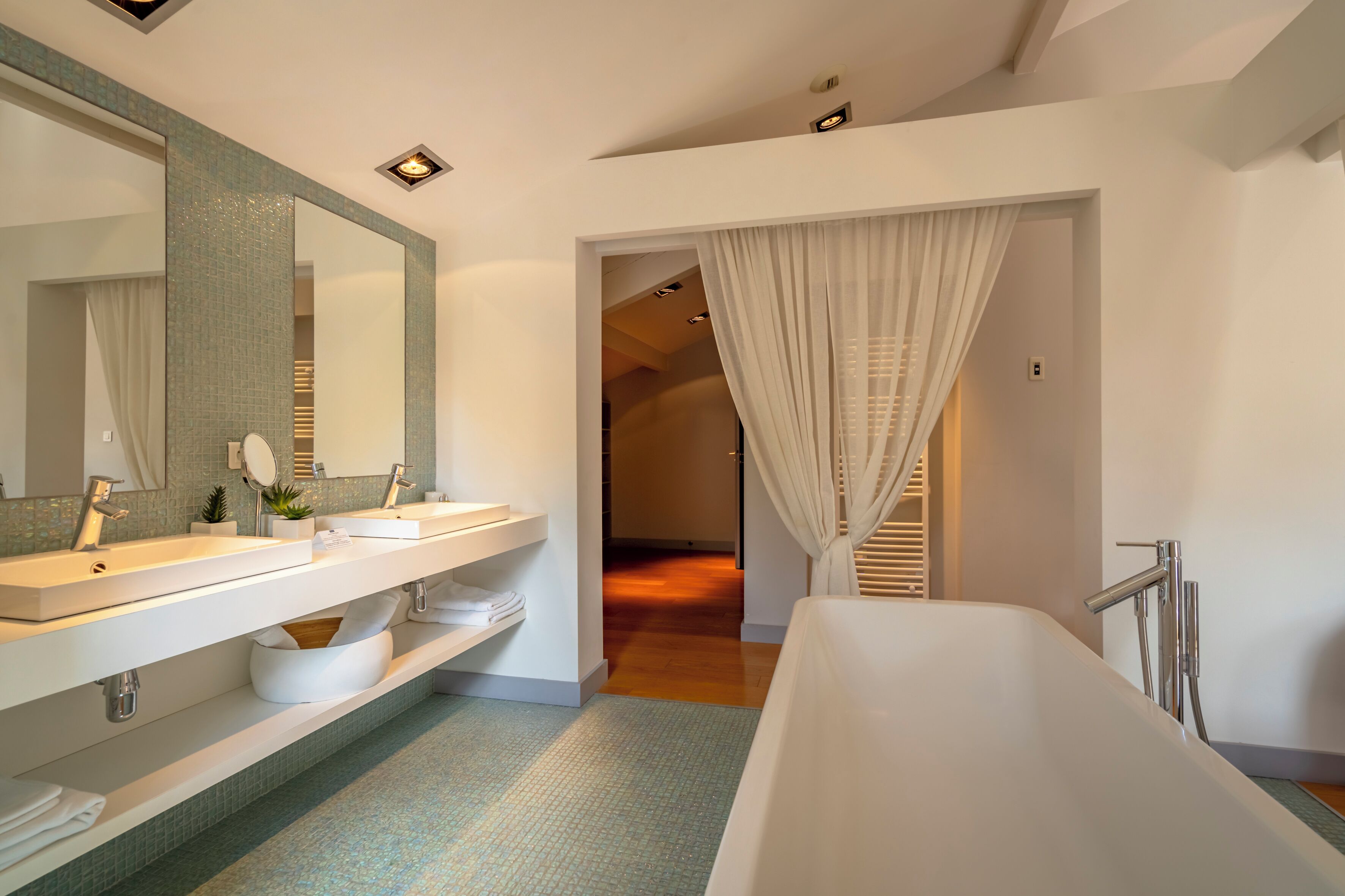 Un baño moderno con un espejo grande, dos lavamanos, una bañera y una ducha.