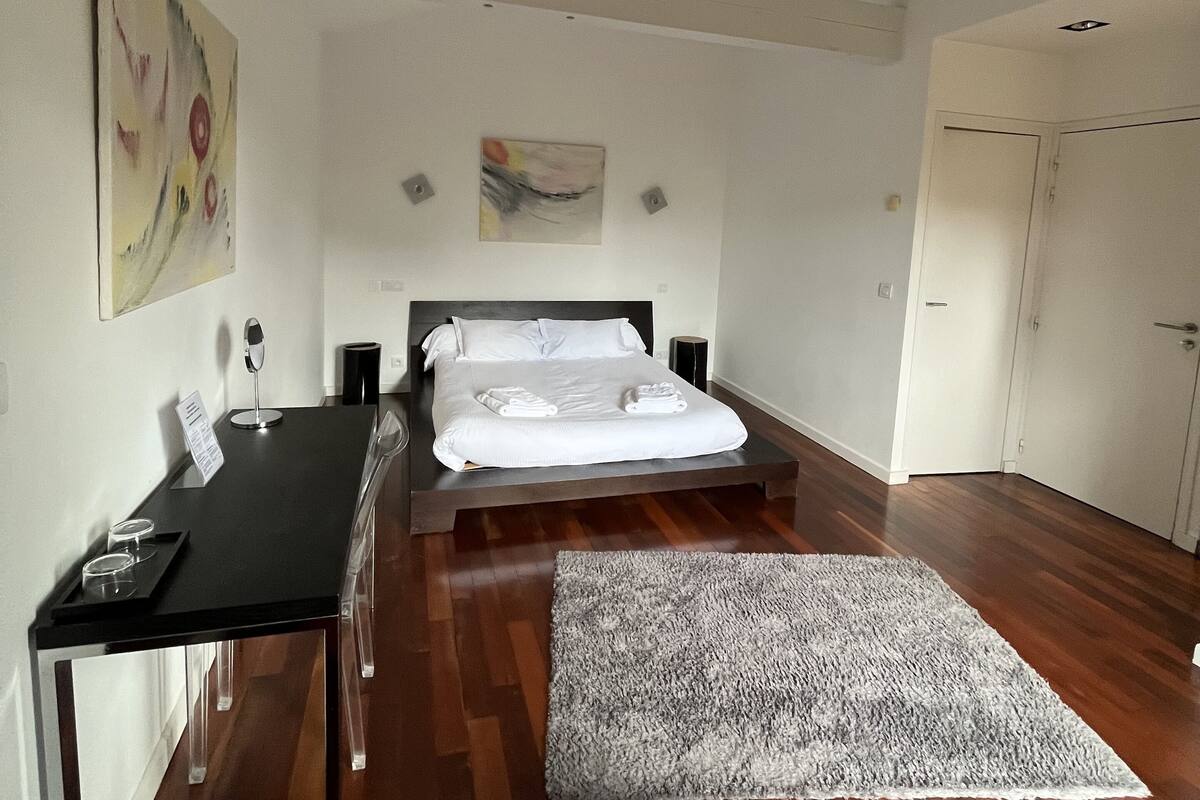 A modern bedroom with a bed, bedside table, and a red chair.