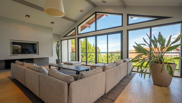 A modern living room with a large sectional sofa, a flat-screen TV, and large windows offering a view of the outdoors. - Lafitenia Resort (Saint-Jean-de-Luz)