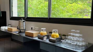 A modern kitchen with a long counter, a coffee maker, and a juice dispenser.