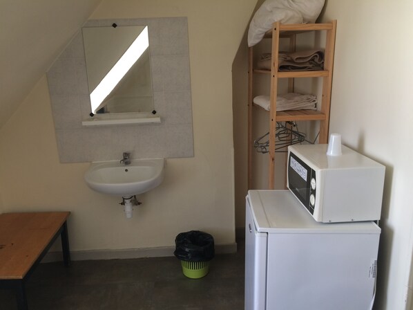 A small bathroom with a sink, mirror, and a shelf with towels.