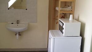 A bathroom with a sink, mirror, and a small refrigerator. - Au Royal Mad Hotel (Paris)