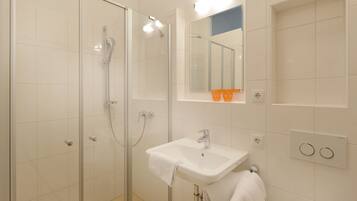 A modern bathroom with a glass shower enclosure, a white sink, and a mirror above it.
