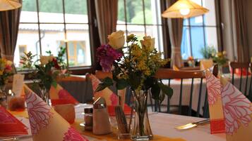 A dining table with a vase of flowers, a candle, and a menu.