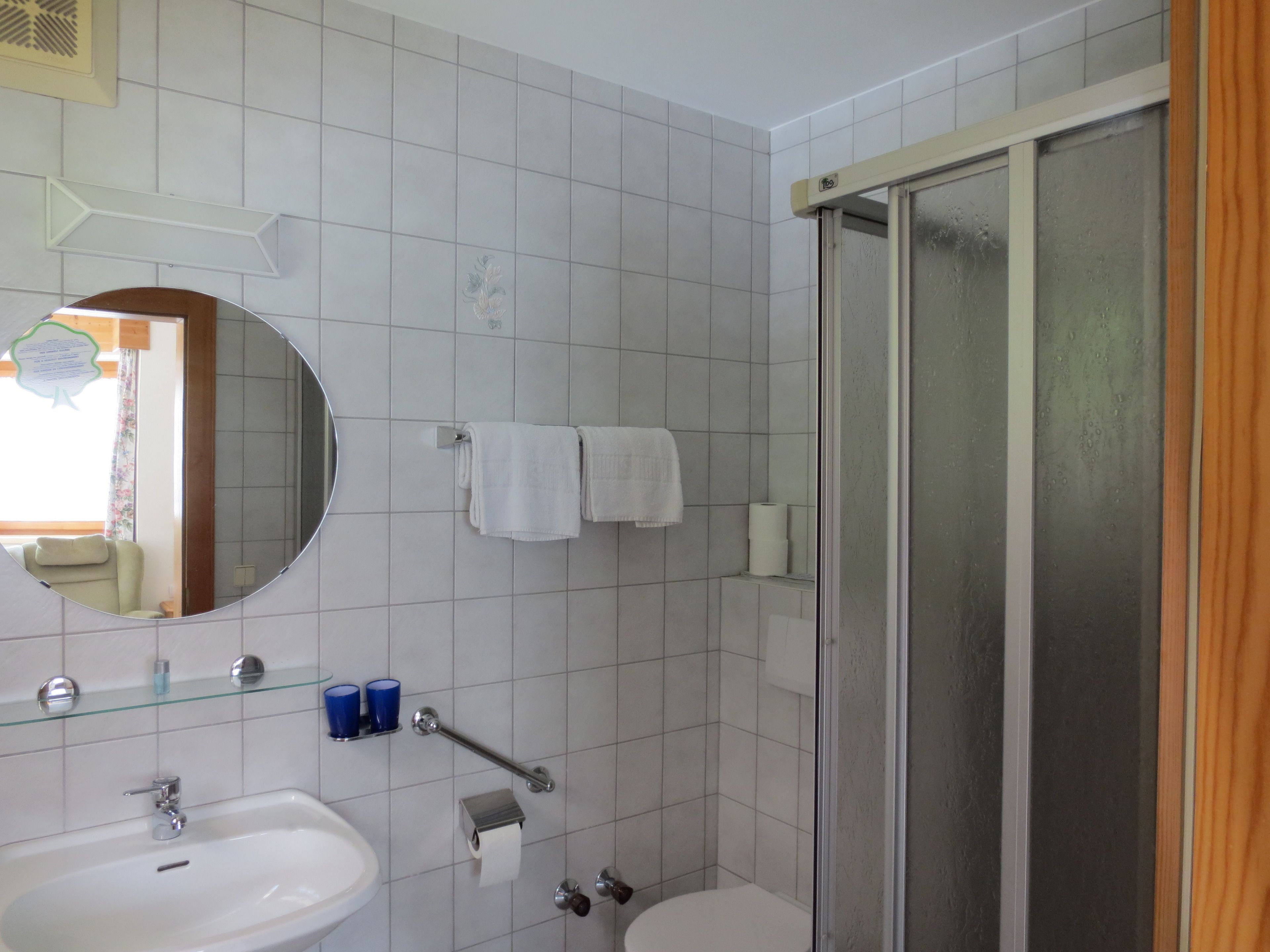 Un baño con lavamanos, espejo, inodoro y cabina de ducha de vidrio.