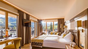 Habitación de hotel con cama, escritorio, silla y vistas a las montañas.