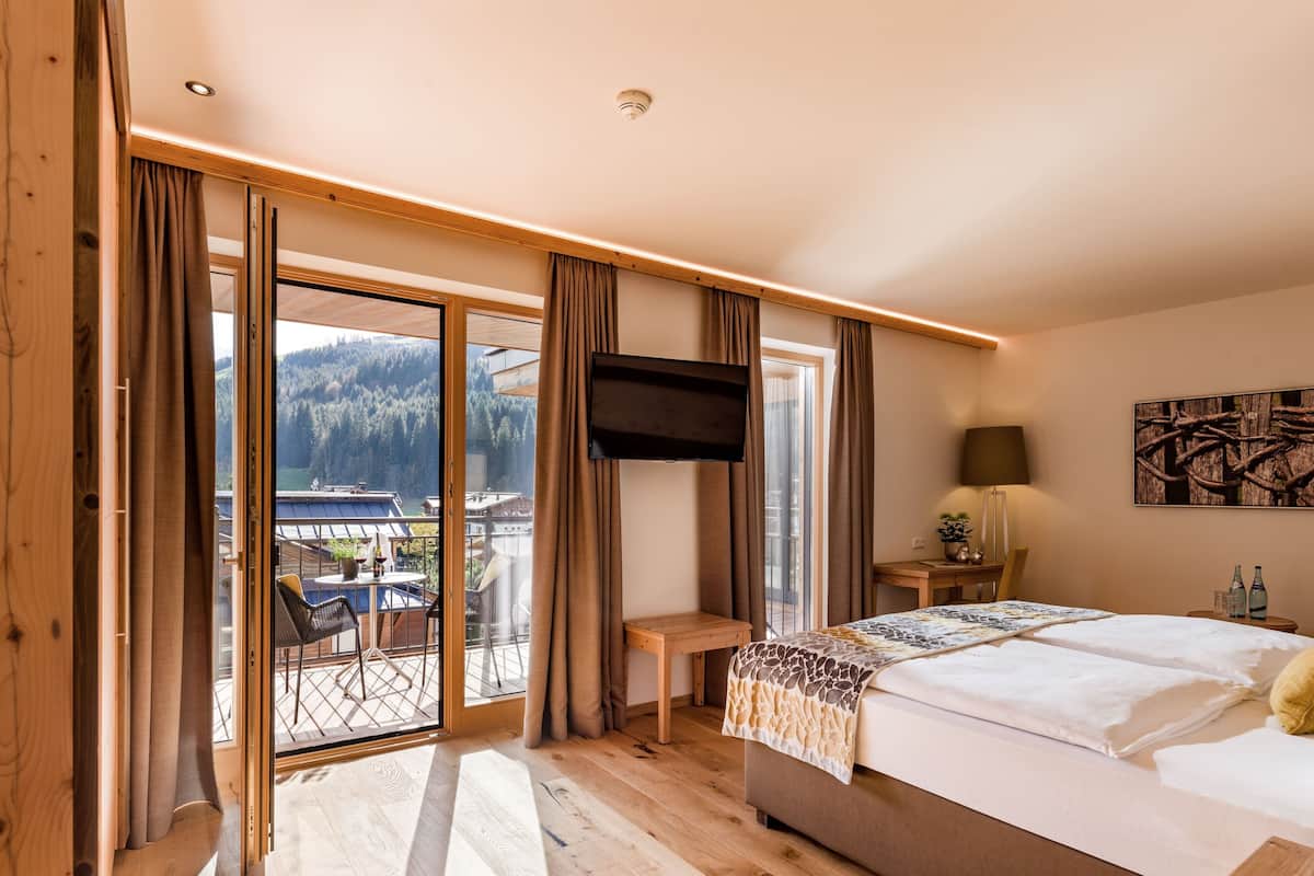 Ein Schlafzimmer mit einem großen Bett, einem Fernseher, einem Schreibtisch und Blick auf einen Berg.