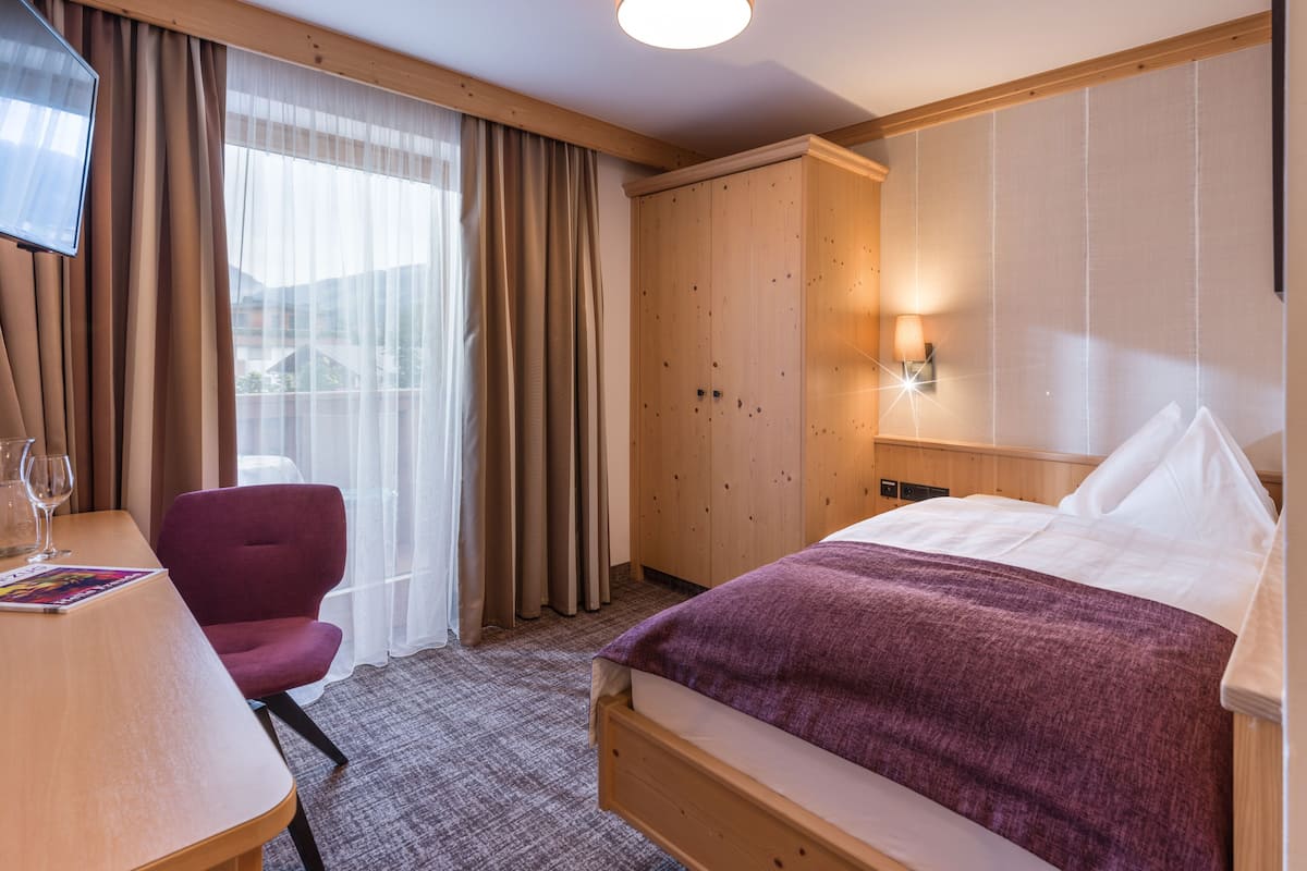 Ein Hotelzimmer mit Bett, Schreibtisch mit Stuhl, Fernseher und Kleiderschrank.
