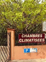 Une enseigne indiquant « CHAMBRES CLIMATISÉES », avec un panneau indiquant un parking en dessous.
