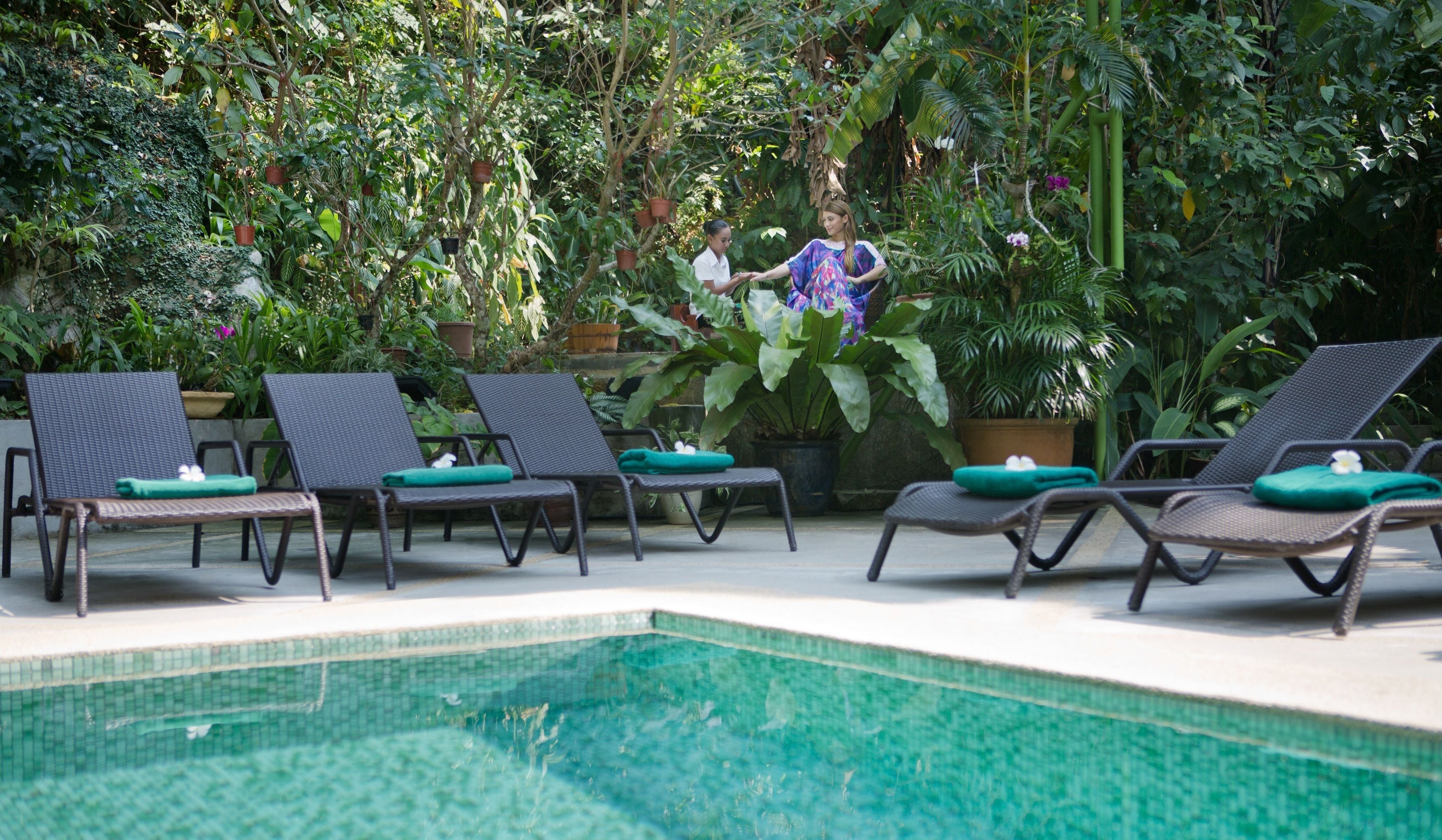 Un espace aménagé au bord de la piscine, avec des chaises longues et des plantes en pot.