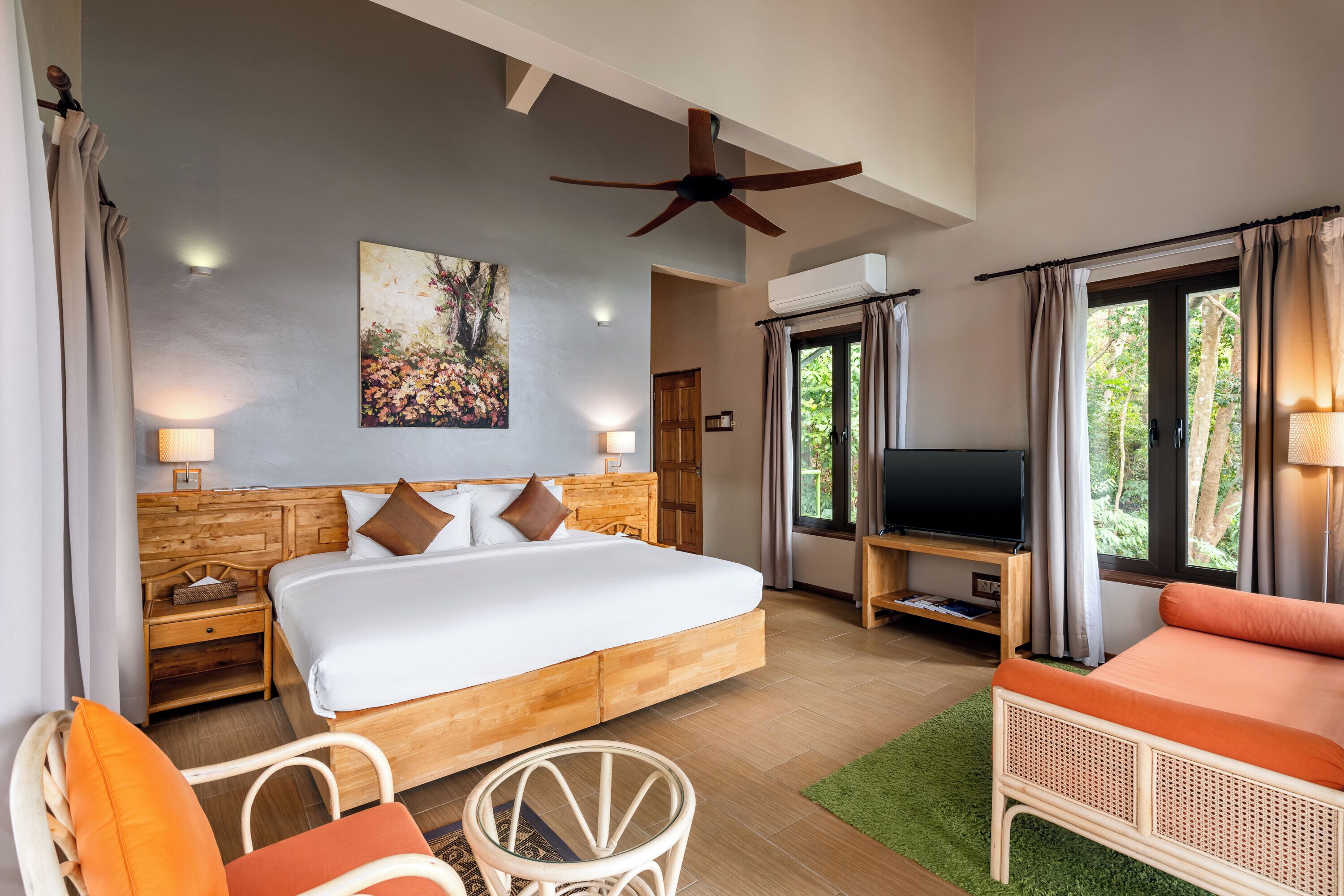 Ein Schlafzimmer mit einem Bett, einem Fernseher, einem Holz-Kopfteil, einem Deckenventilator und einem Fenster mit Vorhängen.