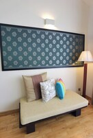 A room with a sofa bed, a patterned wall hanging, and a floor lamp.