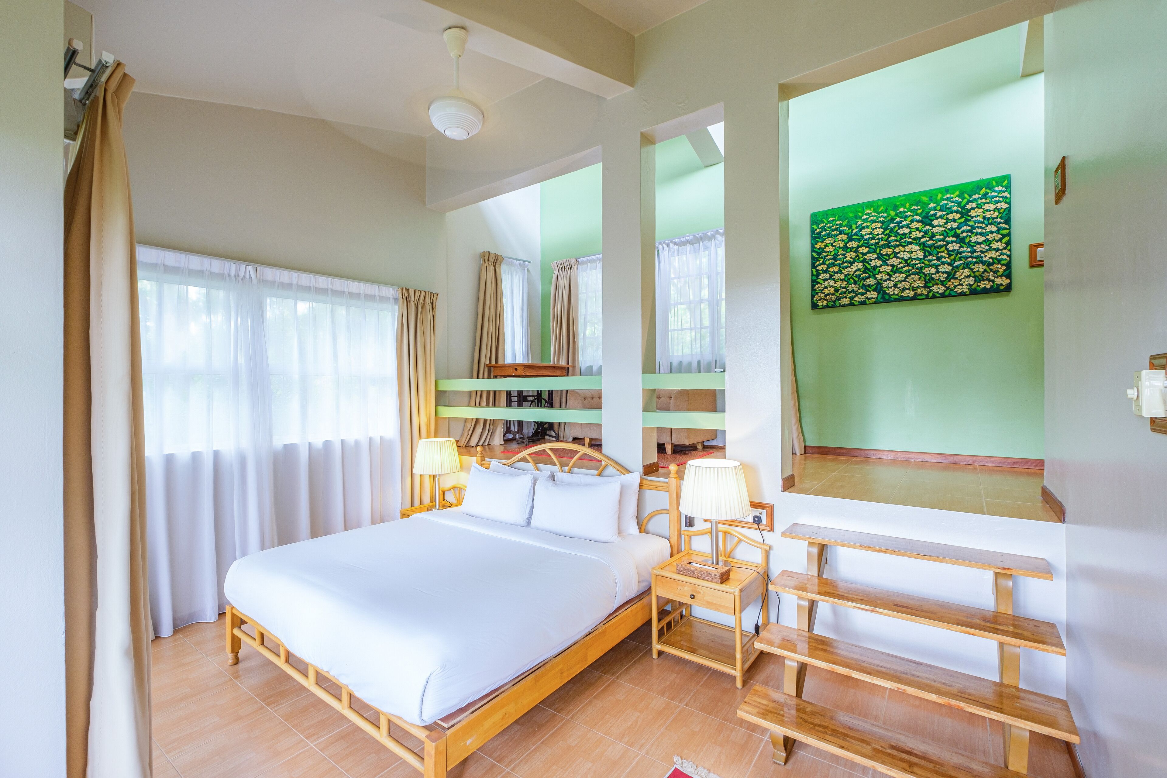 A neatly arranged bedroom with a bed, bedside tables, and a desk.