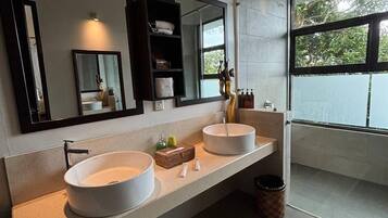 Un baño moderno con dos lavamanos grandes, un espejo y una zona de ducha.