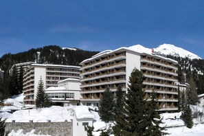 A multi-story hotel with balconies, surrounded by snow-covered landscape and mountains. - Sunstar Alpine Familienhotel Davos (Davos)