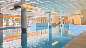 Ein Innenpool mit geometrischem Deckenmuster, großen Glaswänden und einem gefliesten Boden.