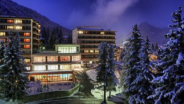 Ein modernes Hotel mit mehreren Etagen, großen Fenstern und einer schneebedeckten Landschaft.