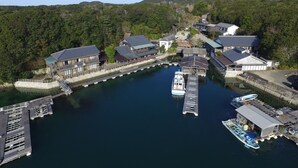 A traditional Japanese village with wooden houses, a small dock, and a boat. - Hiogiso (Shima)