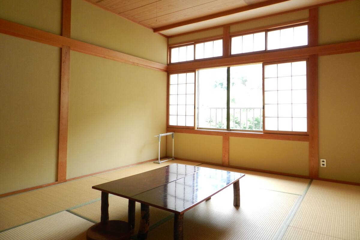 Ein traditioneller japanischer Raum mit Tatami-Böden, einem niedrigen Holztisch und verschiebbaren Shoji-Türen.