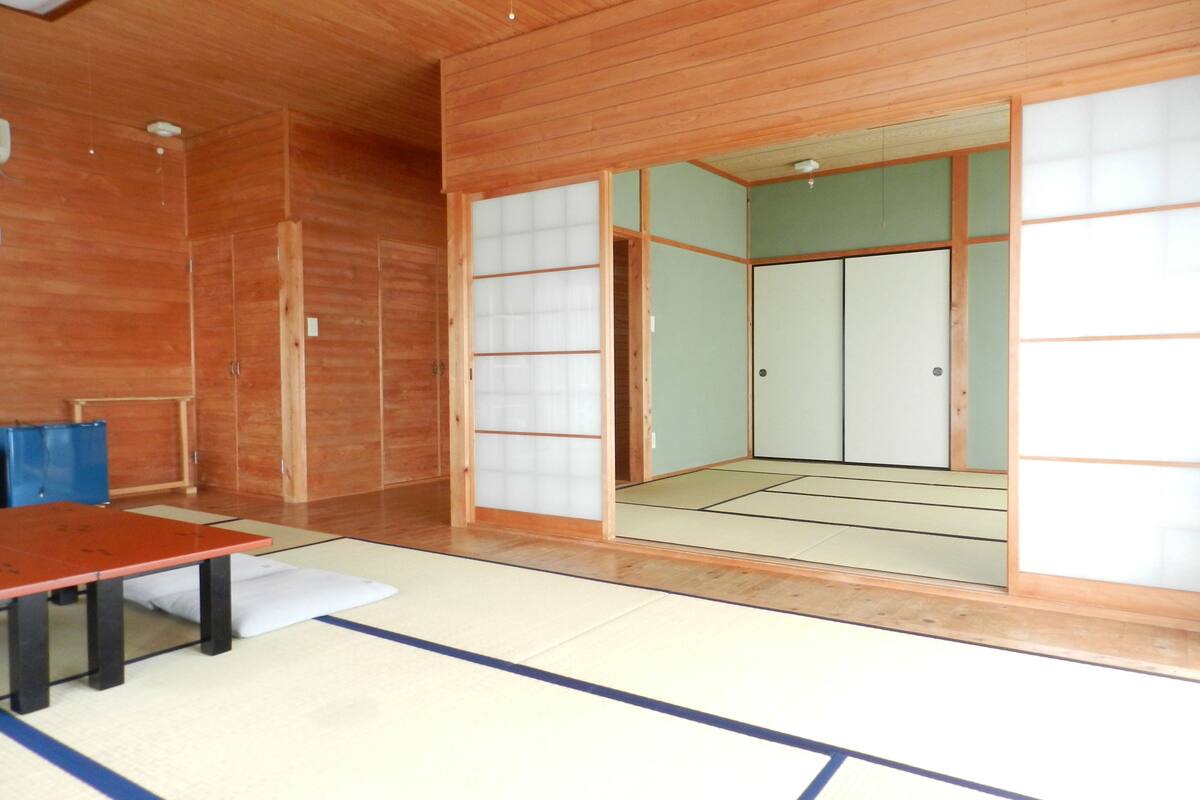 Ein traditioneller japanischer Raum mit Tatami-Böden, Schiebetüren und einer Holzbalkendecke.
