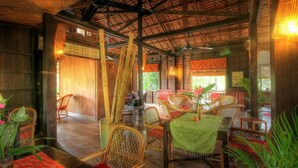 Un interior rústico de madera con mobiliario de bambú, techo de paja e iluminación natural.