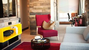 Een moderne woonkamer met een rode fauteuil, een grijze bank en een geel tv-meubel.