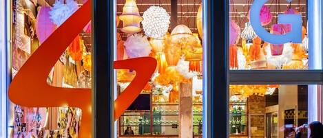 A brightly lit interior with hanging decorative lights, a bar area, and red seating.