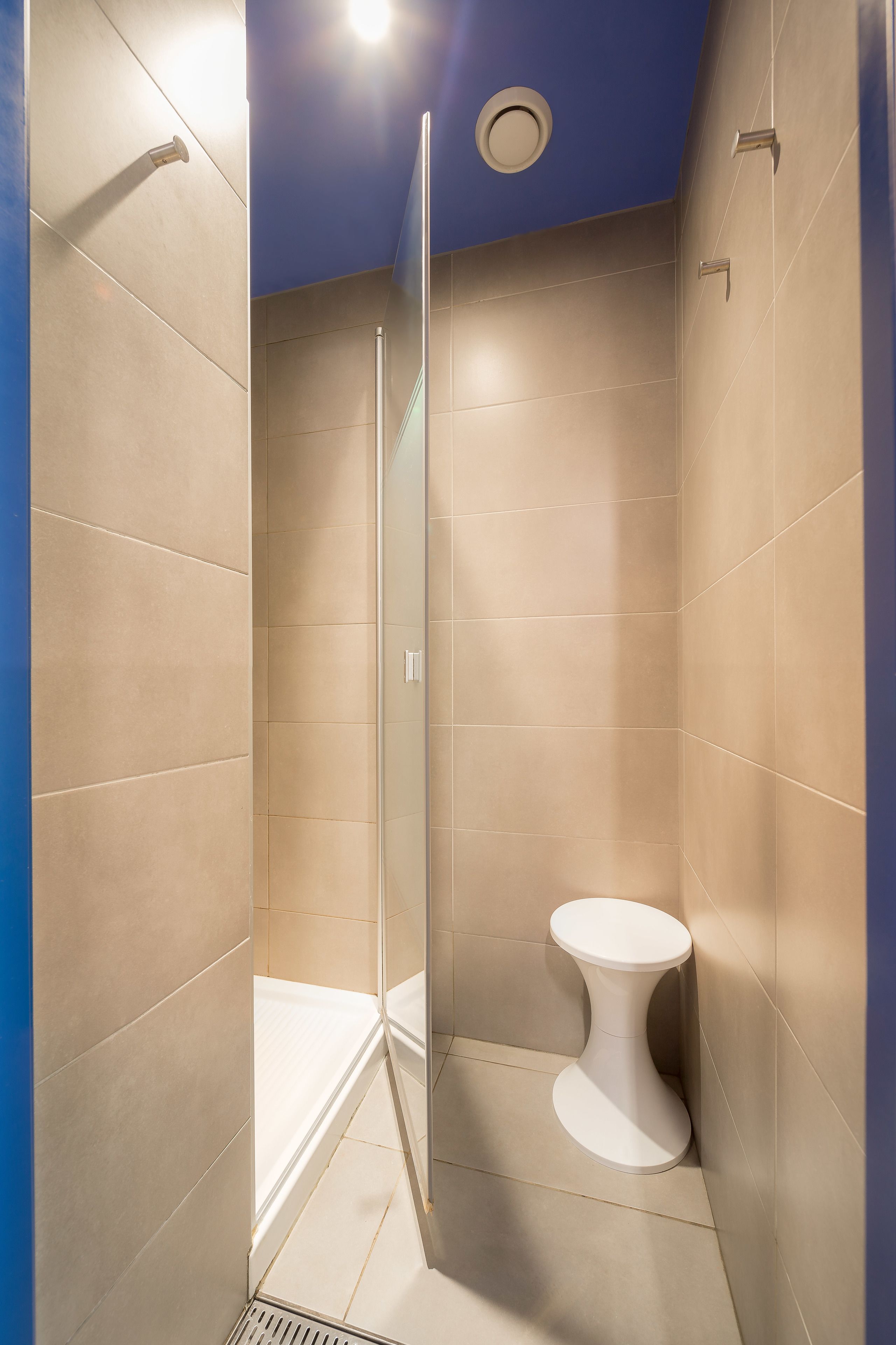 Une salle de bain moderne avec une douche à parois de verre, des toilettes blanches et des carreaux de couleur beige.