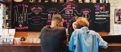 A bar with a chalkboard menu featuring various drink options and a neon sign.