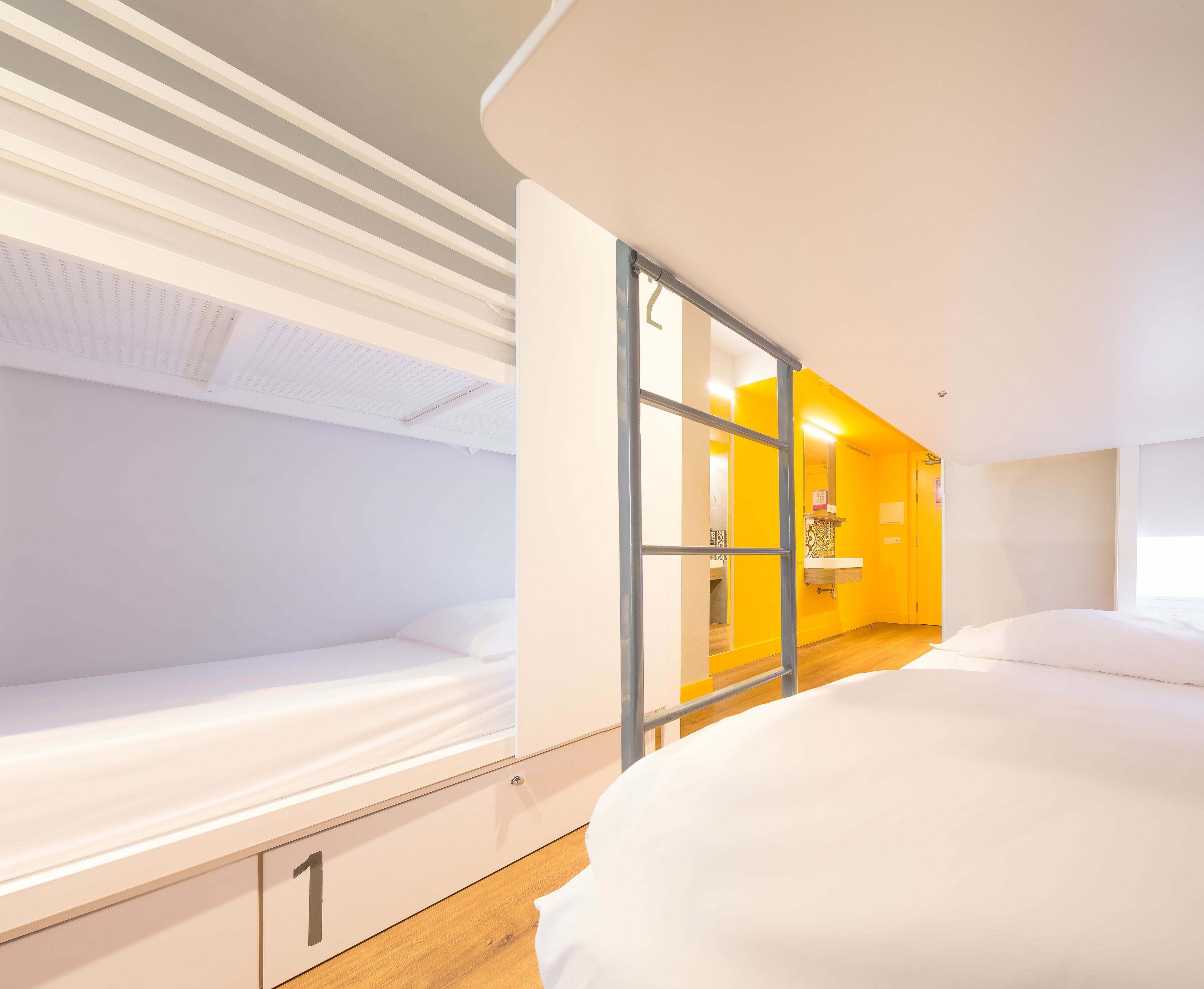 Habitación de hotel con dos camas, baño con lavamanos y ventana.