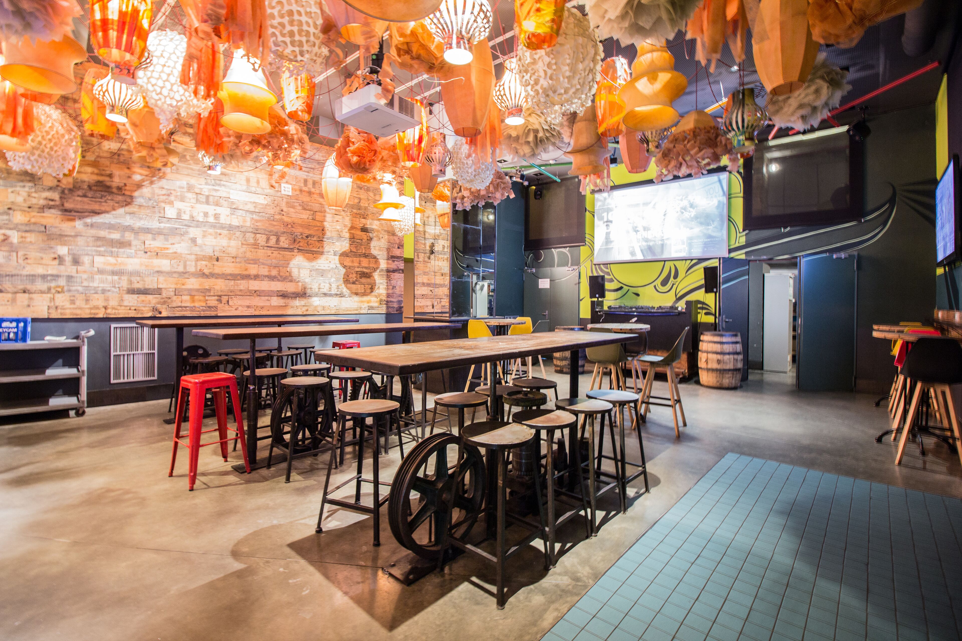A restaurant with a brick wall, wooden tables, and red stools.