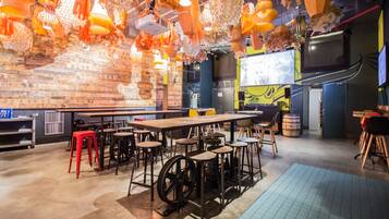 A restaurant with a brick wall, wooden tables, and red stools.