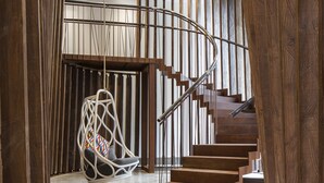 Een modern interieur met een spiltrap, een hangstoel en houten wandbekleding.