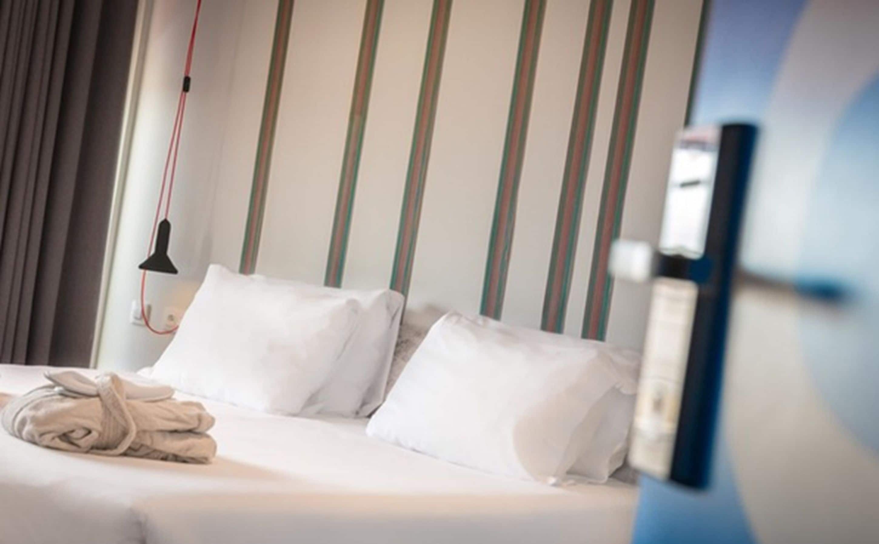 Een hotelkamer met een bed, kussens en een badjas.