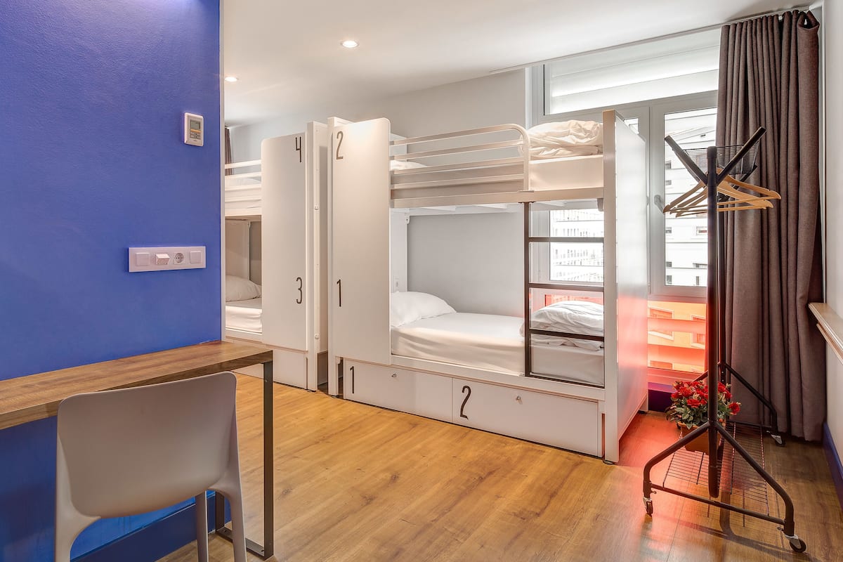 A hotel room with bunk beds, a desk, and a chair.