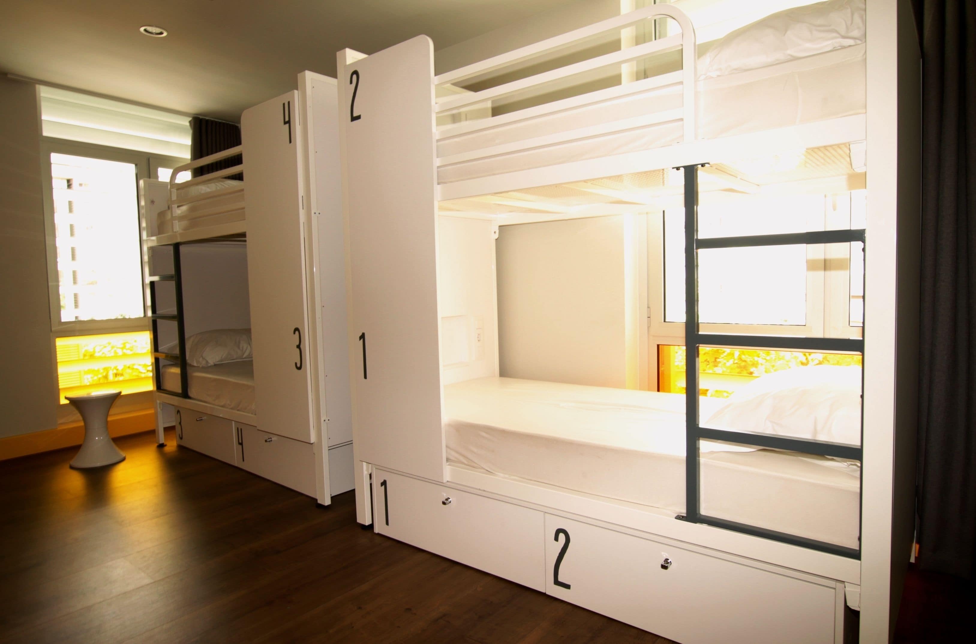 A room with bunk beds, a small table, and a window with curtains.