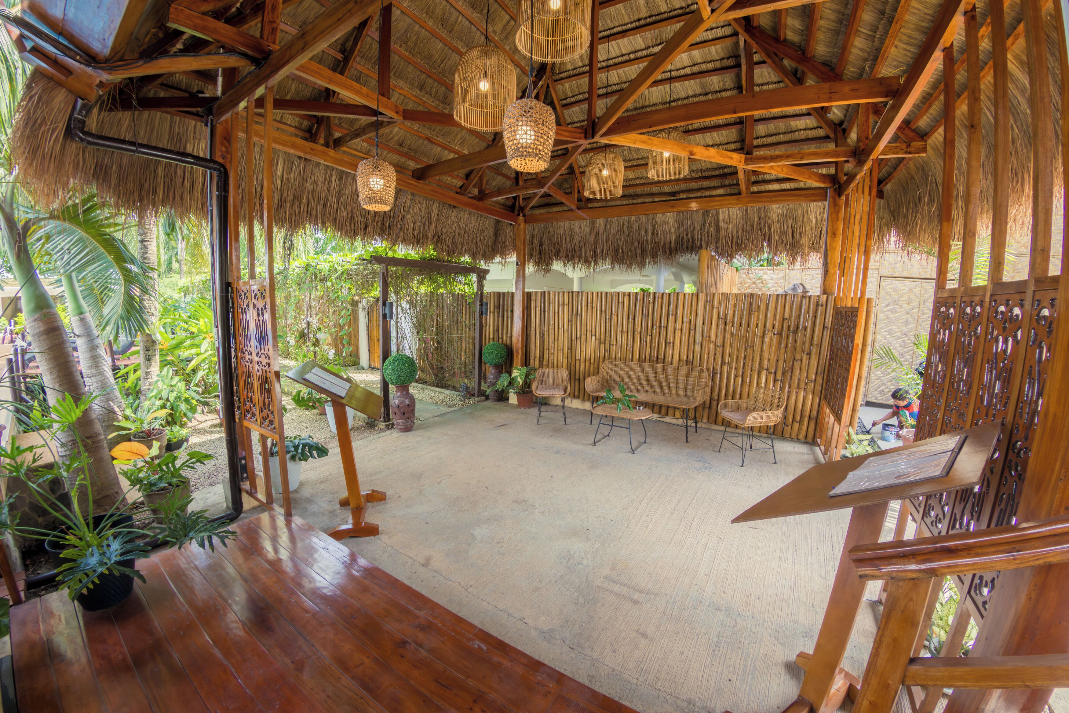 A wooden interior with a thatched roof, bamboo walls, and hanging light fixtures.